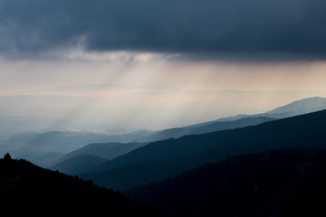 Layered mountain slopes and clouds in blue shades