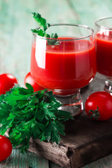 Glasses of tomato juice with vegetables on wooden background, healthy drink