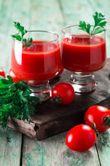 Glasses of tomato juice with vegetables on wooden background, healthy drink