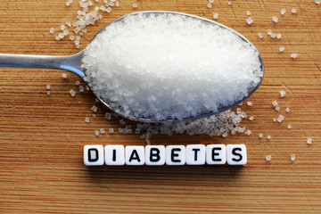 Diabetes block letters in crossword and sugar pile on a spoon 