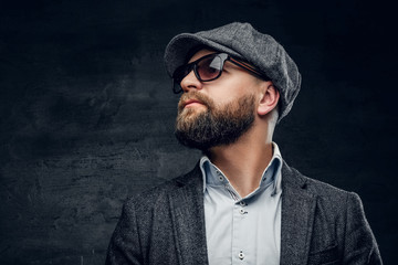 Obraz premium A bearded male in sunglasses and a tweed cap.
