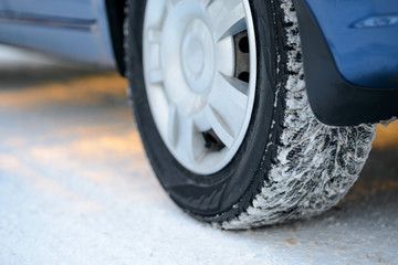 Naklejka na ściany i meble Close-up Image of Winter Car Tire on the Snowy Road. Drive Safe.