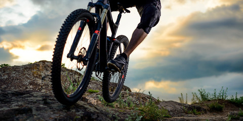 Fototapeta na wymiar Professional Cyclist Riding the Bike Down Rocky Hill at Sunset. Extreme Sport. Space for Text.