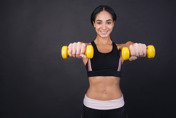Fototapeta na wymiar Young pretty woman holding dumbbells in both hands