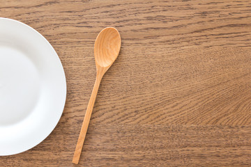 half white empty plate with a spoon on wood table