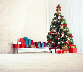 Christmas tree with present boxes over white brick wall