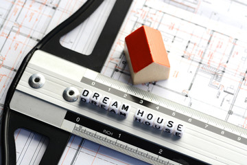 New house project with dream house text on ruler. Architecture plan and small model house on background