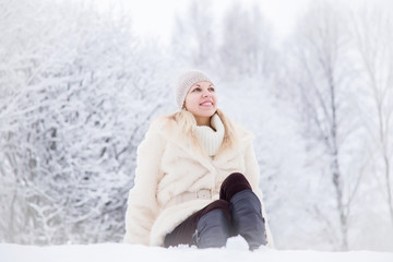 Fototapeta na wymiar Woman wearing soft fur coat and enjoying a beautiful winter day and fresh air in the park.