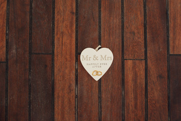 Wooden heart with lettering 'Mr & Mrs happily ever after' lies o