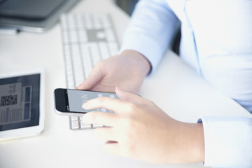 Fototapeta premium Private banking. Close-up shot of a businesswoman sitting at office in front of computer and using cellphone while banking online. 