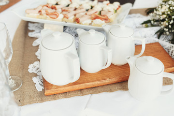 White teapots stand on wooden tray