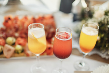 Champagne flutes with fruits stand on dinner table with snacks