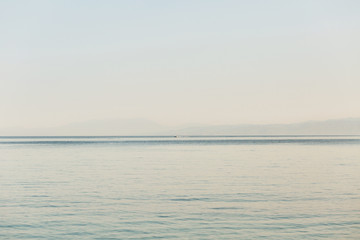 Look from the shore at endless sea and boat in it