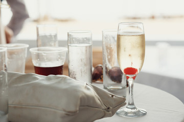 Champagne flutte with cherry stands on dinner table behind littl