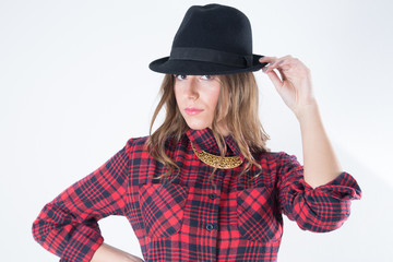 Closeup Portrait Of Fashionable Woman In Red Woolen Plaid Shirt With Black Hat And Golden Necklace Looking At The Camera, Studio Shot Against White Background
