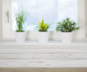 Wooden table on blurred spring window with plant pots background