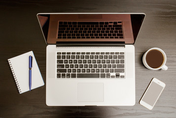 Open the laptop, mug of coffee, notepad and telephone on a black background, top view