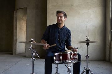 Feel the rhythm. Full length shot of a young musician hitting drums and cymbal while practicing for...