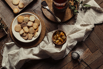 Hot tea in antique cup holder with sugar cookies on old brown wooden background. Rustic style. Top view.