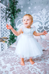 happy little girl in white dress standing in the Christmas decorated room