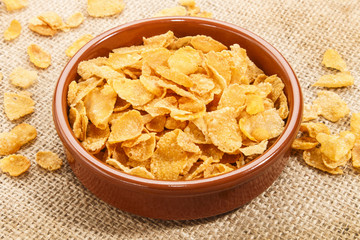 cornflakes in a brown bowl on jute