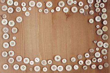 Old vintage buttons frame border on wooden background.