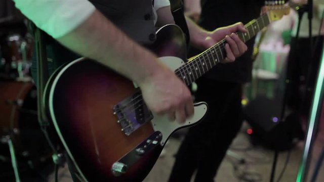 Playing ska rock music concert gig. Man hands play electric guitar pressing note chords close-up. Guitarist fingers hold pick stum strings intensively. Boys band performs at prom party