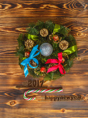 Obraz na płótnie Canvas New Year composition with a wreath, ball, toys and bows. Candy cane. Hash tags 2017 and the new year. On a wooden background calcined. Photo toned. Soft focus.
