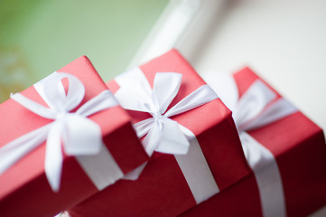 red boxes of gifts tied with a white ribbon near the window