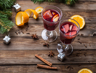 Two glasses of hot mulled wine with oranges, apples and spices