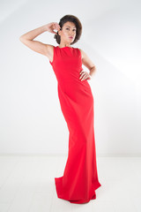Full-Length Studio Shot Of Gorgeous Woman In Red Long Dress Posing With Raised Hand Over White Background