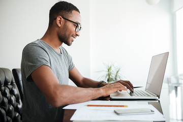 African young man using laptop and sitting at the table