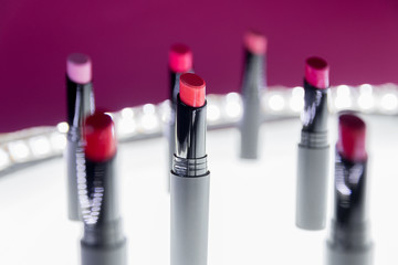 Set of matte Lipstick in red and natural colors on white and pink background. Fashion colorful lipsticks. Professional makeup and beauty. Blinking bokeh background.