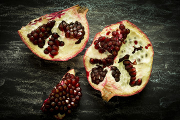 Pomegranate fruit cut in half on a dark background, showing red seeds. Healthy eating, diet or cooking concept. Vegan food. Raw food.