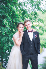 Groom and bride together. couple hugging. Wedding day. Beautiful bride and elegant groom walking after wedding ceremony. Luxury bridal dress and bouquet of flowers. Bride and groom at wedding day