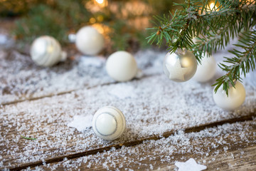 Fototapeta na wymiar White Christmas balls, evergreens and snow on wooden underground