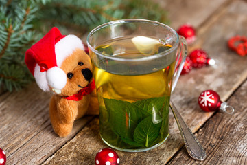 Little Santa bear embracing a cup of hot mint tea