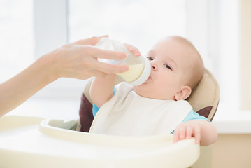 Mom is feeding her baby a bottle of milk