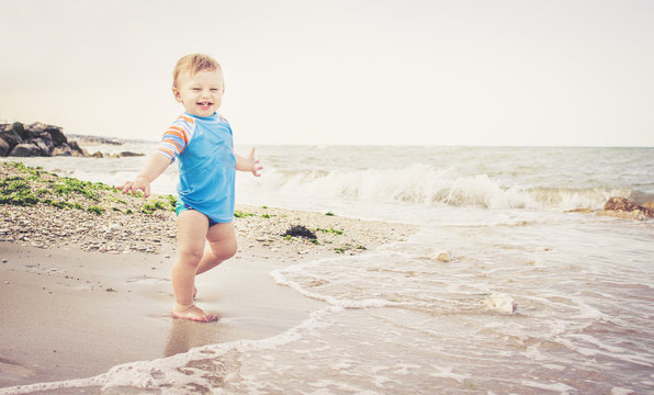 One year old boy is playing on the beach