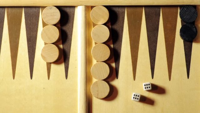 Panning shot of a backgammon board with dice, double six.