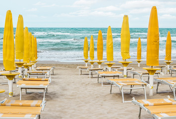 Rows of closed umbrellas and deckchairs on the empty beach