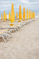 Rows of closed umbrellas and deckchairs on the empty beach