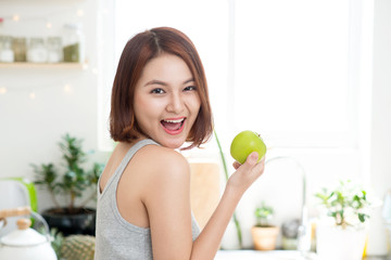 Happy Young Asian Woman Eating Green Apple on Kitchen. Diet. Die