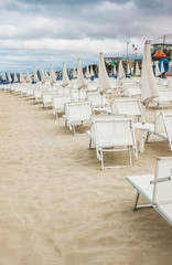 Rows of closed umbrellas and deckchairs on the empty beach