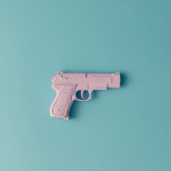 Pink hipster handgun on blue pastel background. Minimal flat lay