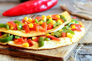 Stuffed omelet on a wooden board. Healthy fried omelet stuffed with red and green bell peppers and corn. Easy vegetarian breakfast omelet recipe. Rustic style. Closeup