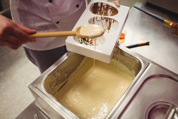 Fototapeta premium Mid section of worker filling chocolate mould
