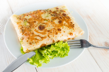 Stuffed pancakes on light wooden background