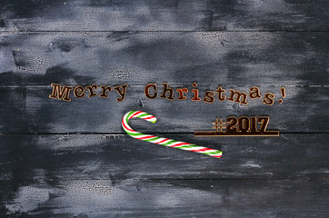 Christmas composition.Wooden black - white background. Laser-cut hash tags and Christmas greetings....
