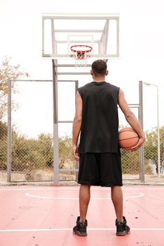 Back View Of Basketball Player Standing And Holding Ball